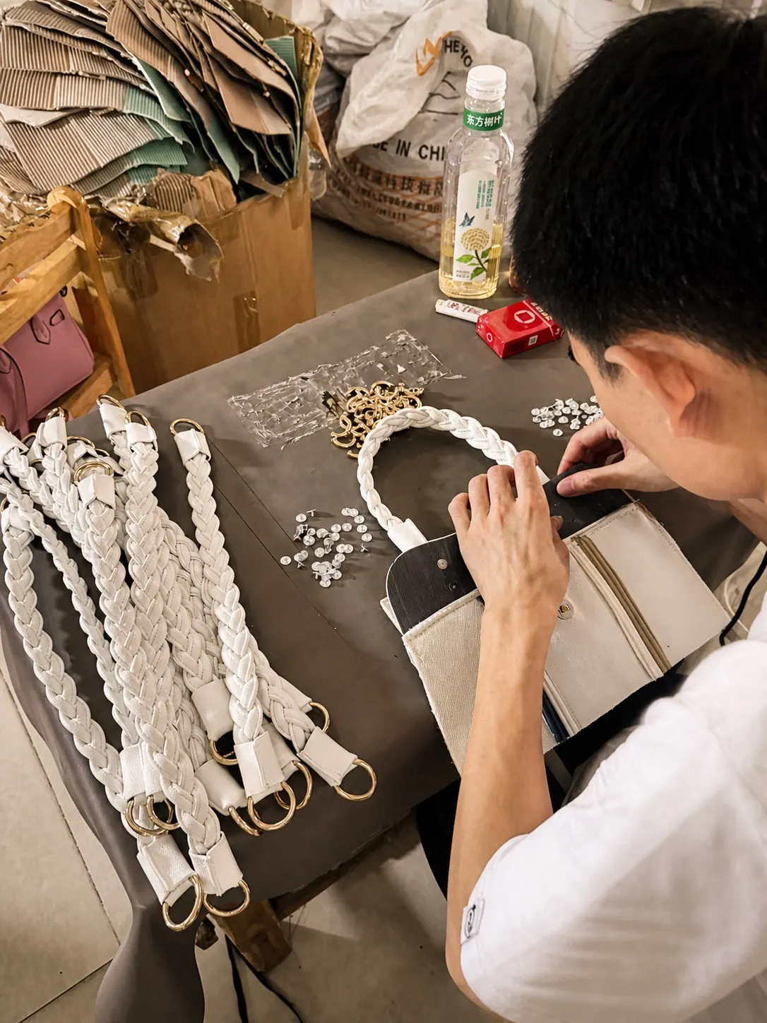 Close-up of an artisan hand-finishing a braided handle on a custom handbag